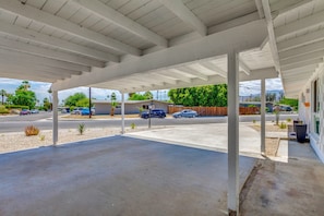 A covered parking area with a concrete floor, a wooden fence, and a row of parked cars. - Thoughtfully Refreshed MCM.  3 Beds with Pool.  28+ day Rentals (Palm Desert)