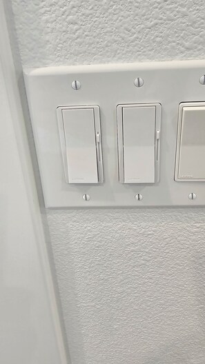 Eine weiße Decke mit drei an der Wand befestigten Lichtschaltern, beschriftet mit 'LUTRON'.