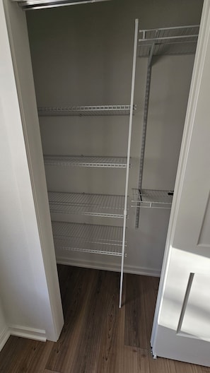 Ein Schrank mit drei Metallregalen und einer weißen Tür.