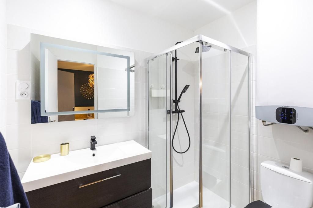 A modern bathroom with a glass shower enclosure, a white sink, and a mirror above it.