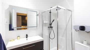 A modern bathroom with a glass shower enclosure, a white sink, and a mirror above it.