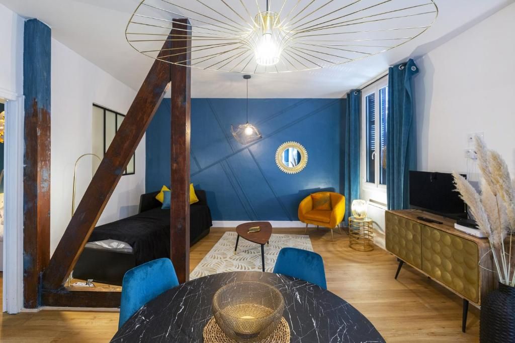 Ein modernes Wohnzimmer mit einem schwarzen Sofa, einem gelben Sessel, einem runden Tisch und einem Fernseher auf einem Schrank.