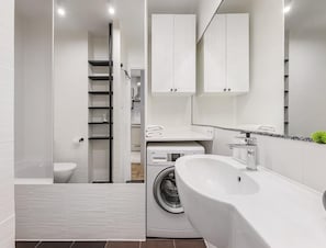 A modern bathroom with a built-in washing machine, a large bathtub, and a toilet. - Warsaw Flat Near Metro (Warsaw)