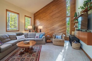 A modern living room with a sectional sofa, a round coffee table, and a fireplace. - The Great Escape - Private Wooded Setting, Hot Tub & Babbling Brook! (Davis)