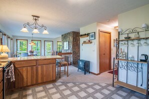 A kitchen with a central island, wooden cabinets, a stone accent wall, and a built-in stove. - The Great Escape - Private Wooded Setting, Hot Tub & Babbling Brook! (Davis)