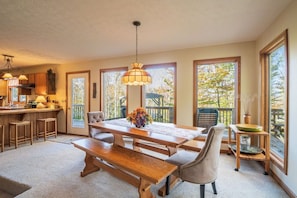 A spacious kitchen with a dining area, large windows, and a view of the outdoors. - The Great Escape - Private Wooded Setting, Hot Tub & Babbling Brook! (Davis)