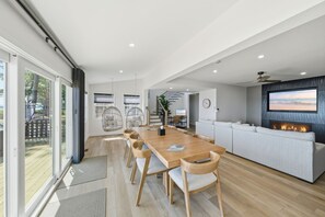 A modern kitchen with a wooden dining table, a built-in oven, and a large island with seating. - Luxury Beach Hs w/ 4 Suites, PrivateBeach & Htub (Heathsville)
