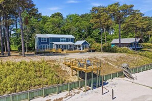 A beachfront property with a large house, a wooden deck, and a sandy beach area. - Luxury Beach Hs w/ 4 Suites, PrivateBeach & Htub (Heathsville)
