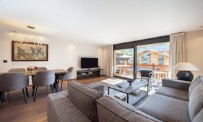 A modern living room with a sofa, coffee table, and dining area. - CENTRAL ZERMATT APARTMENT NEAR SUNNEGGA-EXPRESS & MAIN STREET (Zermatt)