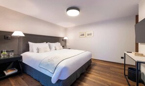 A hotel room with a large bed, bedside tables, a desk, and a ceiling light. - CENTRAL ZERMATT APARTMENT NEAR SUNNEGGA-EXPRESS & MAIN STREET (Zermatt)