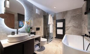 A modern bathroom with a freestanding bathtub, a round mirror, and a glass-enclosed shower. - CENTRAL ZERMATT APARTMENT NEAR SUNNEGGA-EXPRESS & MAIN STREET (Zermatt)