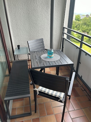 A balcony with a table and chairs, a small table with a cup, and a view of greenery. - Ferienwohnung Bergpanorama - 5 minutes to the bike park and ski lift (Winterberg)