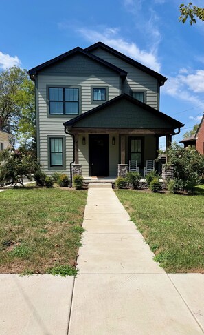 A two-story house with a front porch, a driveway, and a well-maintained lawn. - A modern relaxed retreat in charming historic downtown Springfield! (Springfield)