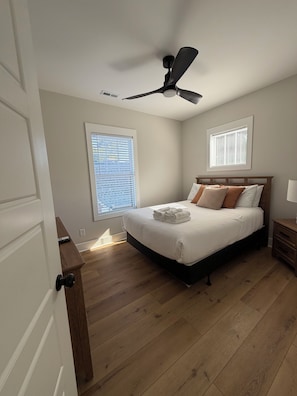 A bedroom with a bed, a ceiling fan, a nightstand, and a window with blinds. - A modern relaxed retreat in charming historic downtown Springfield! (Springfield)