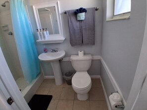 A bathroom with a toilet, sink, and shower curtain. - Fountain Cottages unit 9 (Fort Myers)