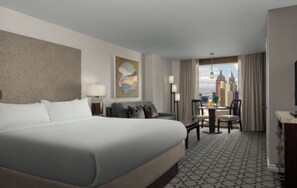 A hotel room with a large bed, a desk, and a chair, a view of the cityscape, and a painting on the wall. - 2BR Vegas Strip Condo at Marriott’s Grand Chateau - Special Deal: Oct 24–31 (Las Vegas)