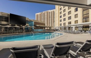 A hotel pool area with lounge chairs and umbrellas, surrounded by high-rise buildings. - 2BR Vegas Strip Condo at Marriott’s Grand Chateau - Special Deal: Oct 24–31 (Las Vegas)
