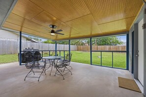 A covered patio with a table and chairs, a ceiling fan, and a view of a backyard with a wooden fence. - Spacious 4BR Retreat Near Lackland AFB & SeaWorld (San Antonio)