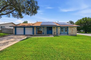 Einbungalow mit einer Steinaußenwand, einer blauen Tür und einer Garage.