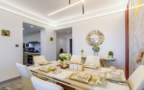 A dining area with a table set for four, a kitchen in the background, and a decorative mirror on the wall. - Beautiful 2-BR Riara 1 apartment near junction mall with fitness room in Nairobi (Nairobi)
