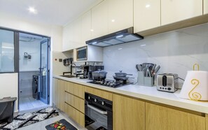 A modern kitchen with a built-in oven, a coffee machine, and a toaster. - Beautiful 2-BR Riara 1 apartment near junction mall with fitness room in Nairobi (Nairobi)