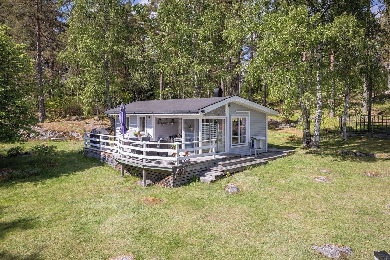 Eine Hütte mit Veranda, umgeben von Bäumen.