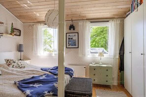 A bedroom with a bed, a nightstand, a dresser, and a window with curtains. - Sandvik Countryside Escape Minutes from the Beach (Linköping)