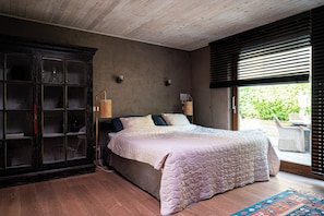A bedroom with a bed, a dark wooden cabinet, and a window with blinds. - Fleur de Jasmin | A Unique Wellness Retreat near Ghent (Sint-Martens-Latem)