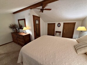 Ein Schlafzimmer mit einem großen Bett, einem Schminktisch, einem Spiegel, einem Deckenventilator und zwei Türen.