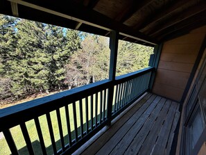 A wooden deck with a railing overlooking a forested area. - Pappadeaux's Roost | Cozy Loft with Wood-Burning Fireplace! (Snowshoe)