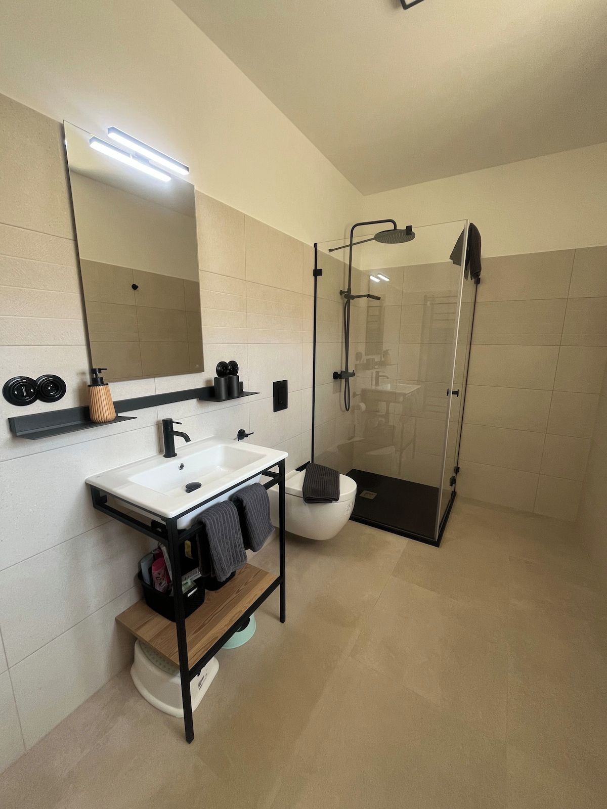 A modern bathroom with a white sink, black faucet, and a glass-enclosed shower.