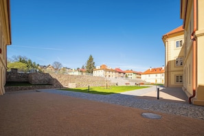 Un cortile con mura in pietra, un'area pavimentata e edifici con tetti rossi.
