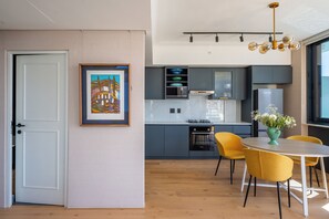 A modern kitchen with a dining area, featuring a Bosch oven, a Bosch dishwasher, and a dining table with yellow chairs. - 2-bedroom Penthouse in the Waterkant Cape Town (Cape Town)