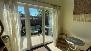 A room with a sliding glass door leading to a patio with a green sofa and a hot tub. - Perfect studio with AC in lovely Santa Cruz 
Minutes from Pleasure Point & Hwy 1 (Santa Cruz)