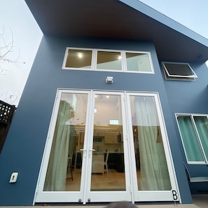 A two-story building with a large sliding glass door entrance, a small window on the upper floor, and a visible light switch. - Perfect studio with AC in lovely Santa Cruz 
Minutes from Pleasure Point & Hwy 1 (Santa Cruz)