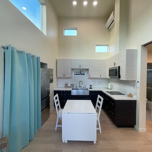 A compact kitchen with a central island, a dining table with chairs, and a window with curtains. - Perfect studio with AC in lovely Santa Cruz 
Minutes from Pleasure Point & Hwy 1 (Santa Cruz)