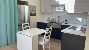 A compact kitchen with a refrigerator, sink, and a dining area with a table and chairs. - Perfect studio with AC in lovely Santa Cruz 
Minutes from Pleasure Point & Hwy 1 (Santa Cruz)