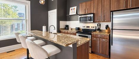 A modern kitchen with a central island, stainless steel appliances, and wooden cabinets.