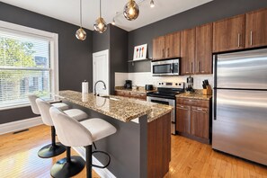 A modern kitchen with a central island, stainless steel appliances, and wooden cabinets.
