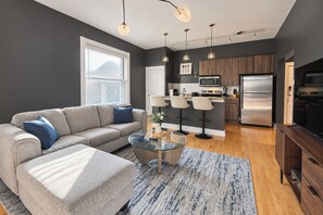 A modern living room with a sofa, coffee table, and a kitchen area in the background.