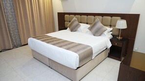 Une chambre d’hôtel avec un lit, une table de chevet, une lampe et un rideau.