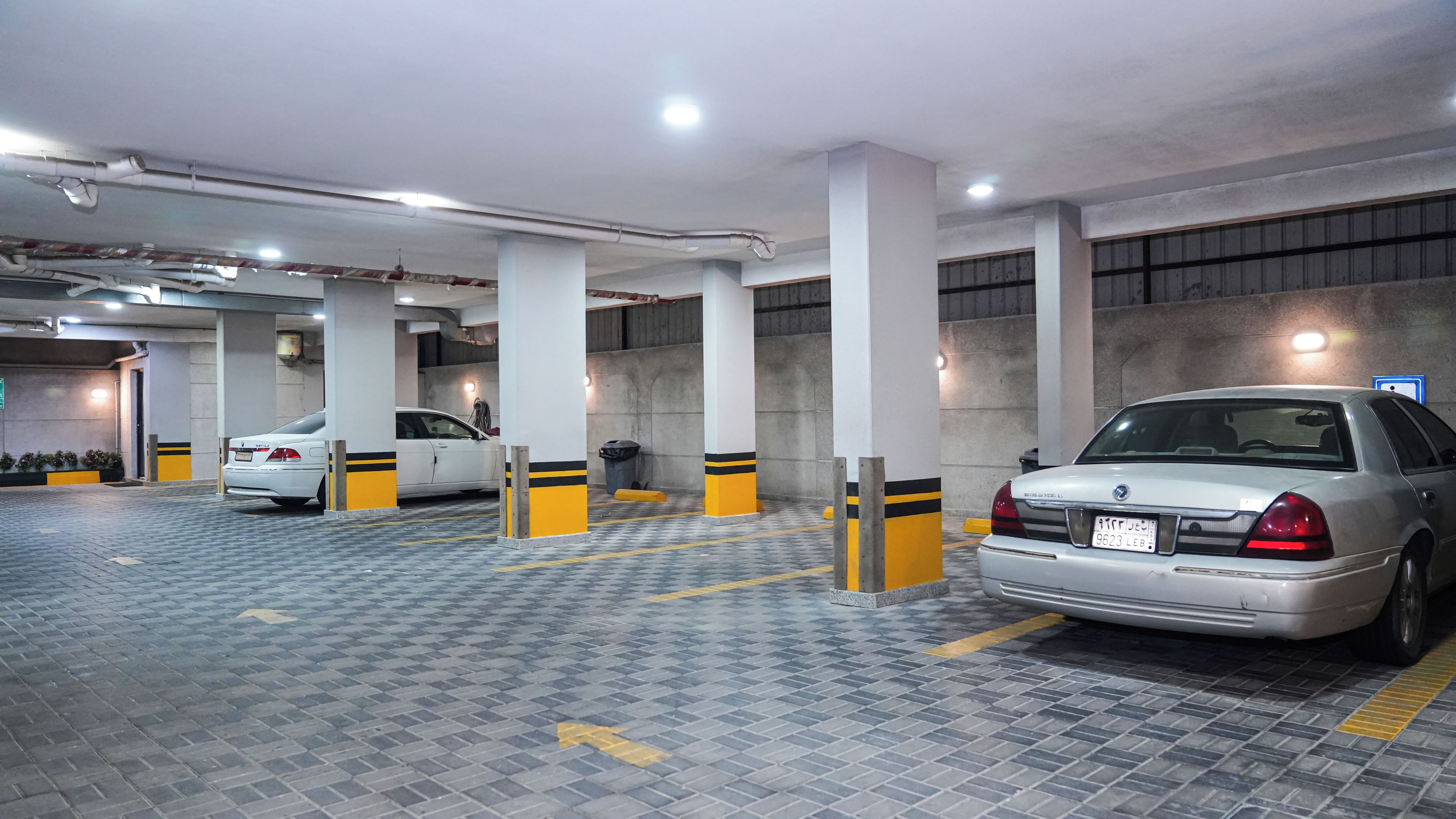 Eine mehrgeschossige Parkgarage mit geparkten Autos, Betonpfeilern und Deckenbeleuchtung.