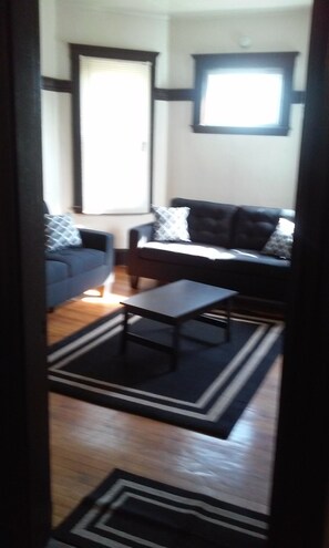 A living room with a sofa, a coffee table, and a rug. - Beautiful 3-bedroom apartment with AC in vibrant Boston (Boston)