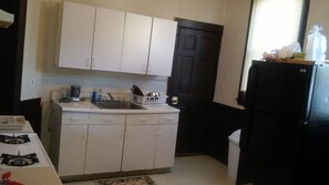 A compact kitchen with white cabinets, a gas stove, a sink, and a black refrigerator. - Beautiful 3-bedroom apartment with AC in vibrant Boston (Boston)