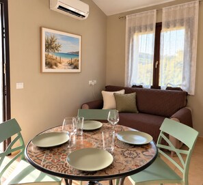 A dining area with a round table, chairs, and a painting on the wall. - New Listing (Sardegna)