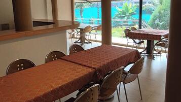 Un comedor con una larga mesa y sillas, un ventilador de techo y vistas a zonas verdes al exterior.