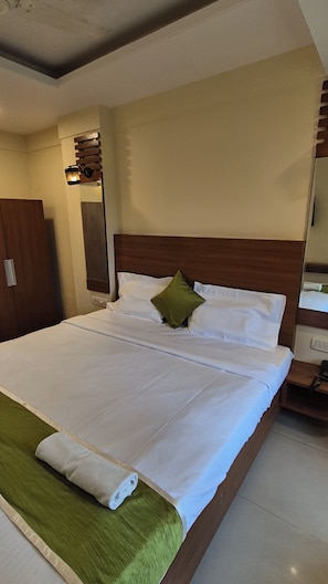 Una habitación de hotel con una cama grande, un cabecero de madera, una mesita de noche y un armario.