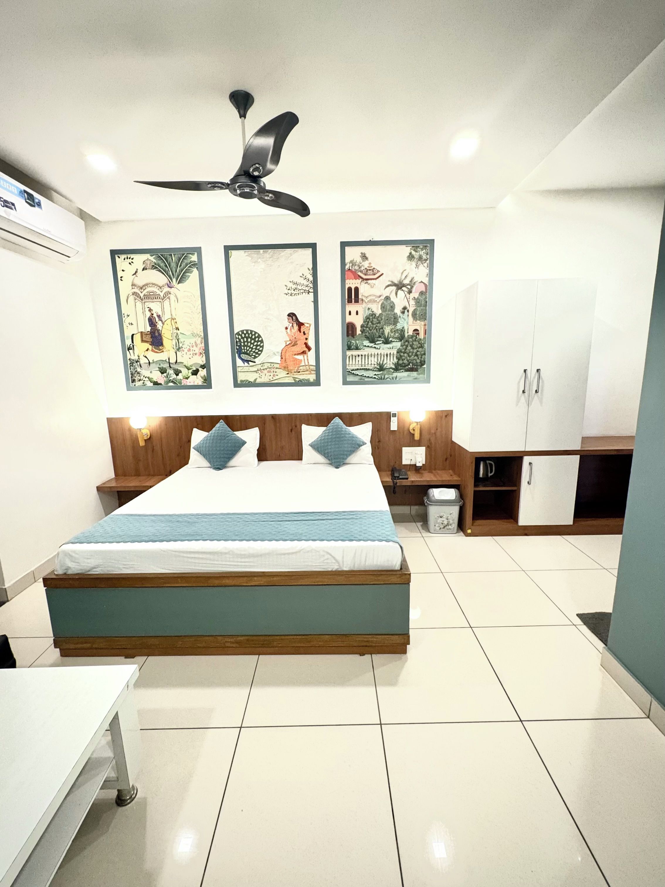 A bedroom with a bed, a ceiling fan, a wardrobe, and wall art.