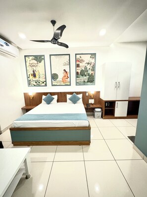 A bedroom with a bed, a ceiling fan, a wardrobe, and wall art.