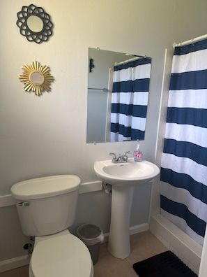 Un baño con inodoro, lavamanos y cortina de ducha.